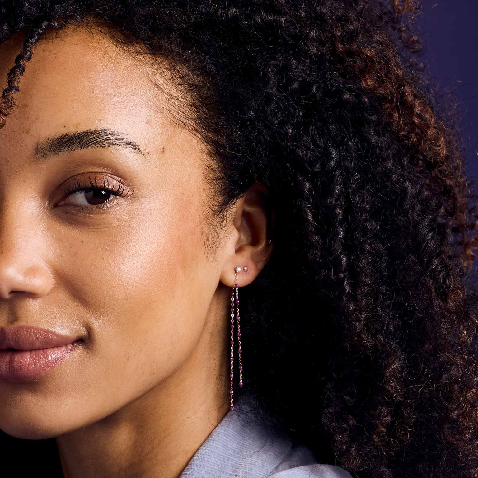 Photo du visage d’une femme portant des boucles d’oreilles Gigi Clozeau de couleur Galaxy.