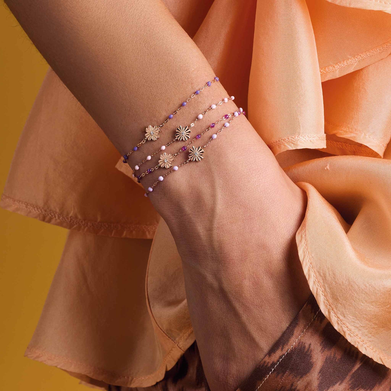 Photo du poignet d'une femme portant des bracelets Gigi Clozeau Trèfle Lumière de différentes couleurs.