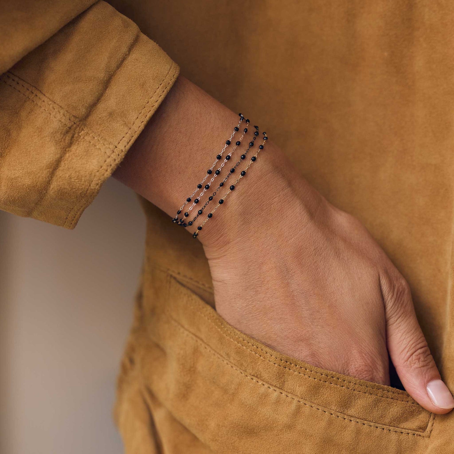 Poignet d’une femme portant différents bracelets de la nouvelle collection en or noir Gigi Clozeau.