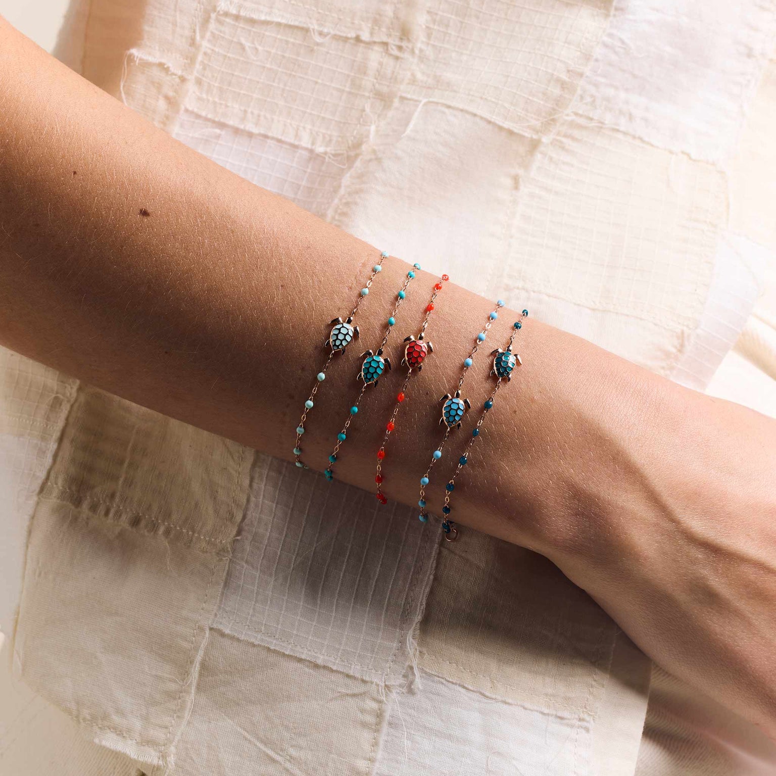 Photo du poignet d'une femme portant des bracelets Tortues Gigi Clozeau de différentes couleurs. 