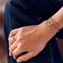 Photo de la main d’une femme portant différents bracelets Gigi Clozeau aux couleurs turquoise et noires.