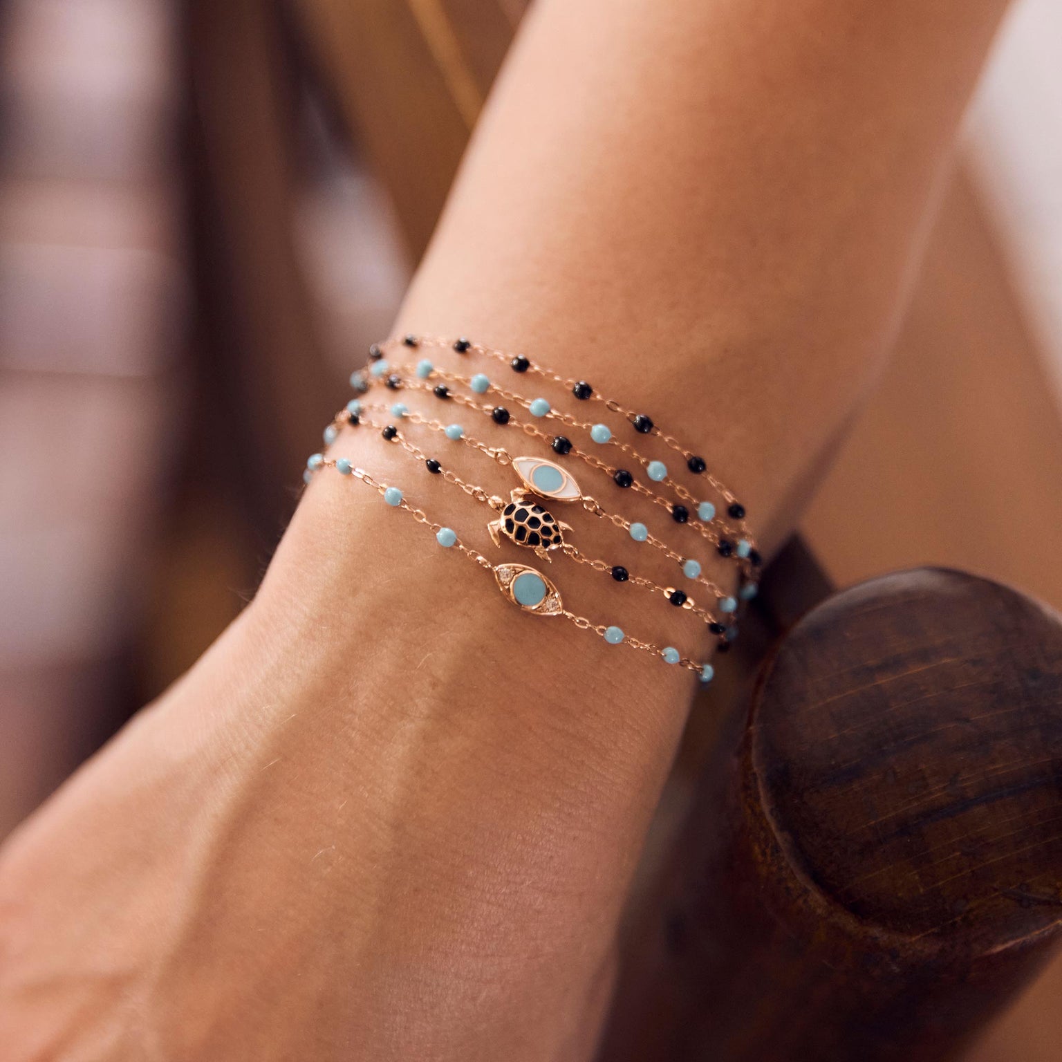 Photo de la main d’une femme portant différents bracelets Gigi Clozeau aux couleurs turquoise et noires.
