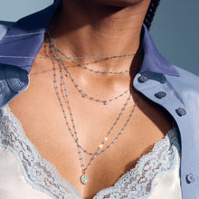 Photo du décolleté d’une femme portant des colliers et pendentifs Gigi Clozeau de la nouvelle couleur azur.