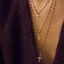 Décolleté d’une femme portant des colliers en or noir Gigi Clozeau.